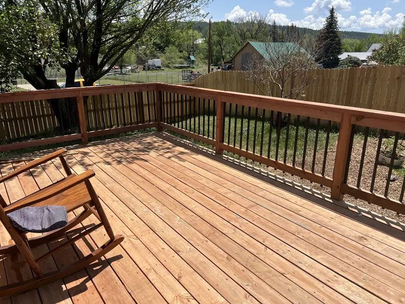 Freshly finished wood deck with a railing and a rocking chair, looking out over a Pagosa neighborhood